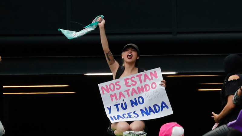 A protester holds a sign reading “They are killing us, and you do nothing”